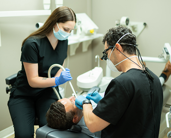 Dentist and dental team member treating dentistry patient