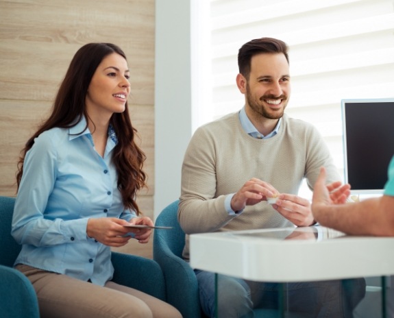 Dentist talking to two smiling dental patients
