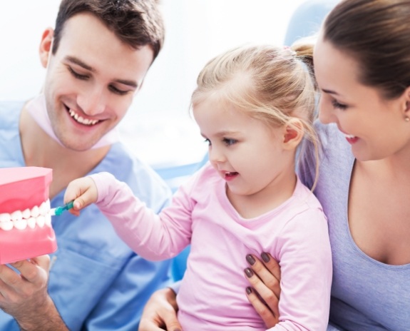 Dentist helping child learn to brush teeth