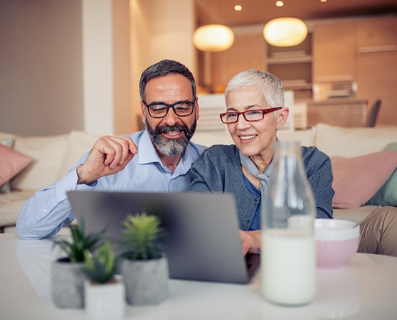 Older couple smiling while using a computer at home