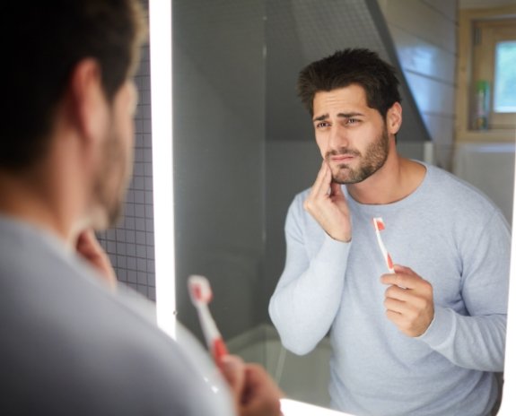 Man holding cheek in pain before emergency dentistry visit