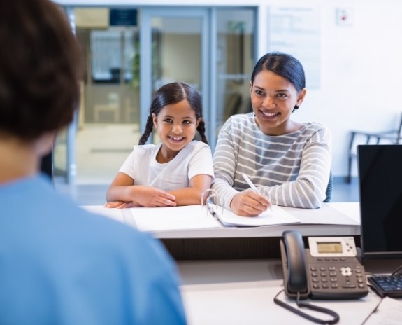 Woman in and child discussing the cost of dental emergencies with dentistry team