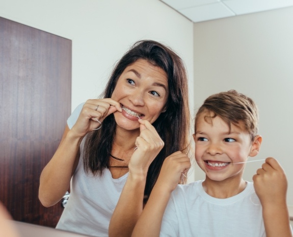 Mother and child flossing teeth together to prevent dental emergencies