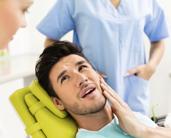 Man in need of T M J therapy holding jaw in pain