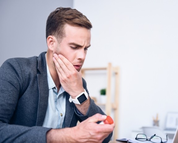 Man in need of occlusal adjustment holding jaw in pain